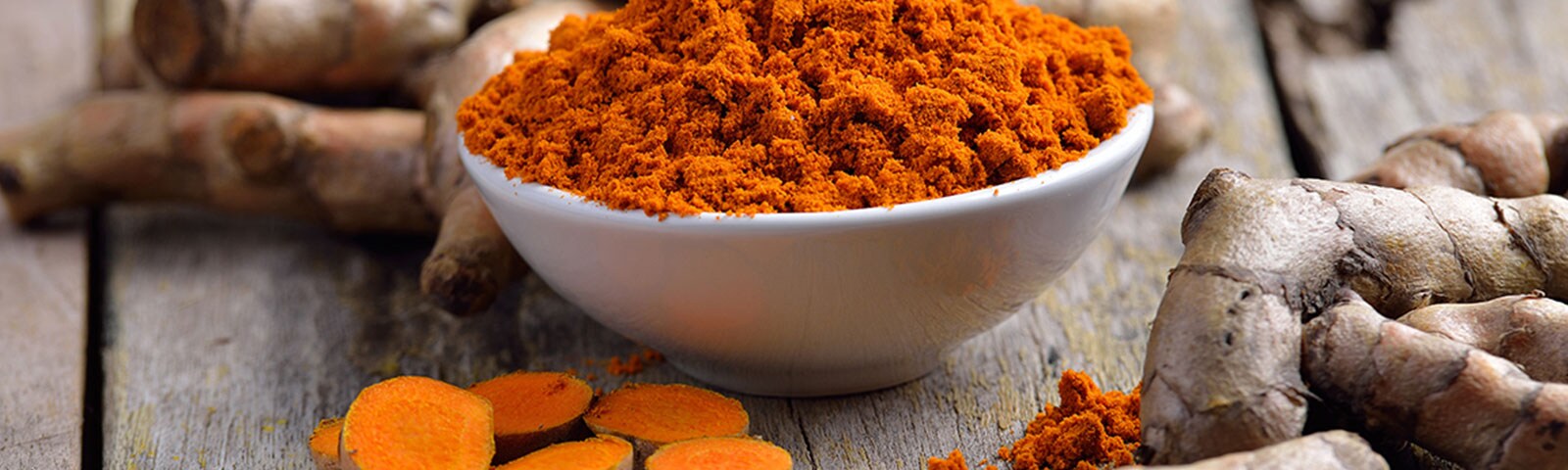 Ground turmeric in a bowl on a wooden table