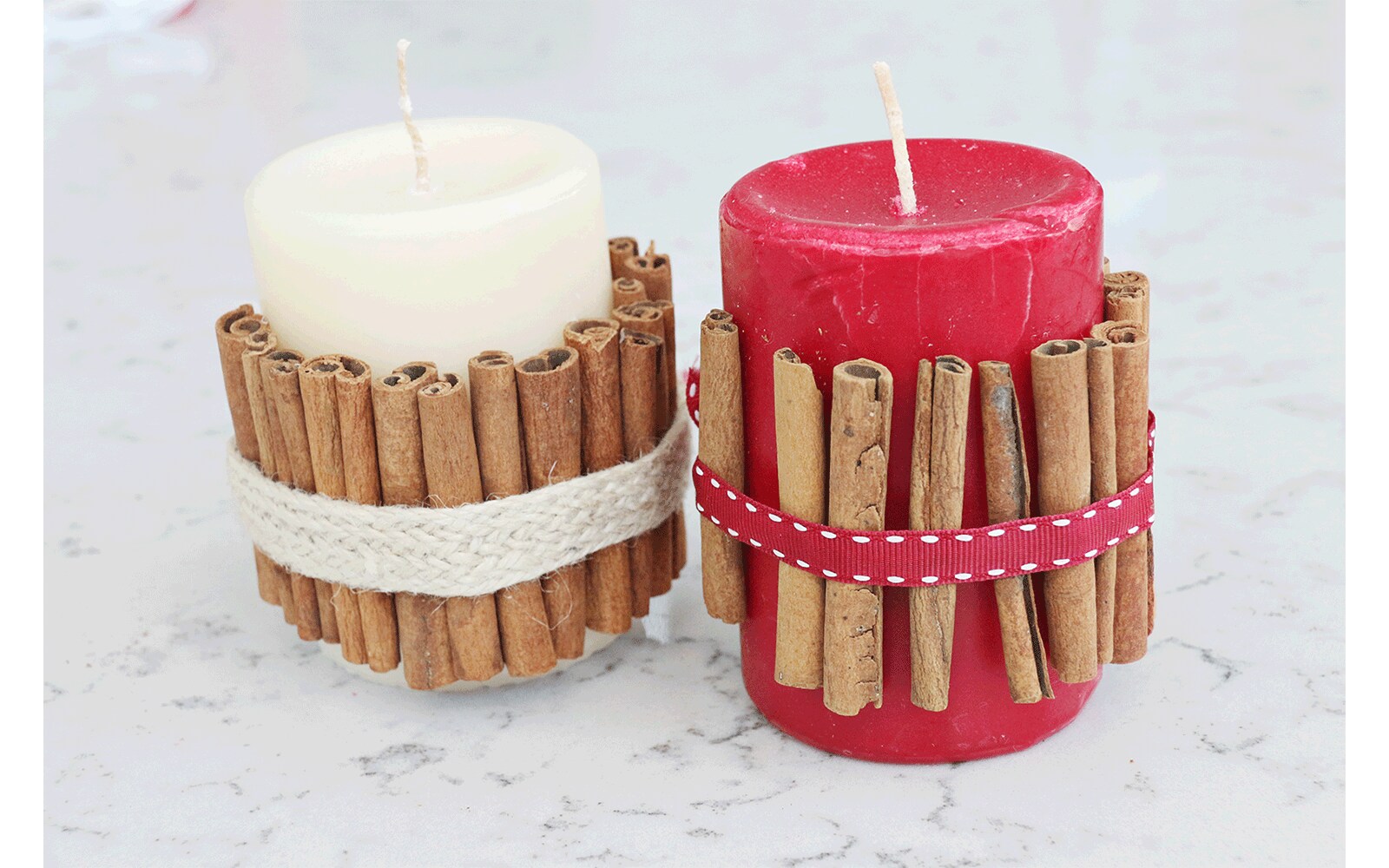 Red candle wrapped in cinnamon sticks held in place with ribbon sits inside of a white lantern with glass windows