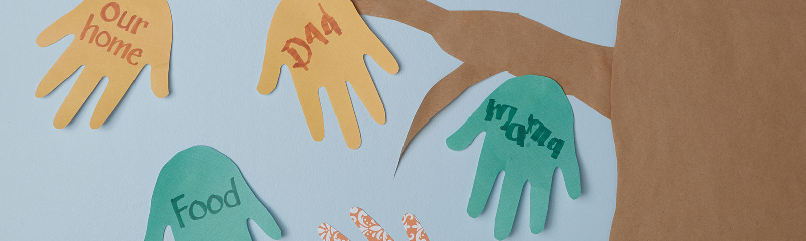 Cutout paper hands being used as leaves on a large paper tree. Each hand labeled with something to be thankful for.