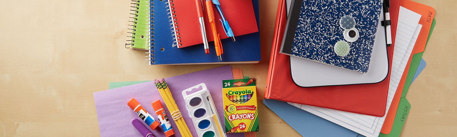 School supplies like notebooks, folders, glue sticks, pencils and pens stacked together on a table School supplies like notebooks, folders, glue sticks, pencils and pens stacked together on a table