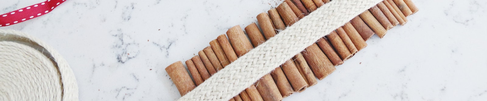 Close up of a red candle wrapped in cinnamon sticks