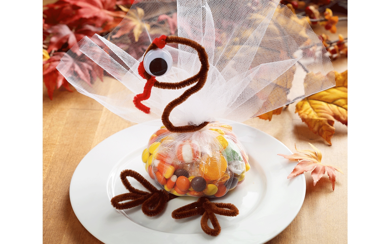 A turkey with a candy body wrapped in tulle, pipe cleaners for legs, and a pipe cleaner neck and head with googly eyes